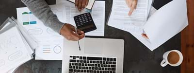 Image of two business owners completing their bookkeeping using a calculator and laptop