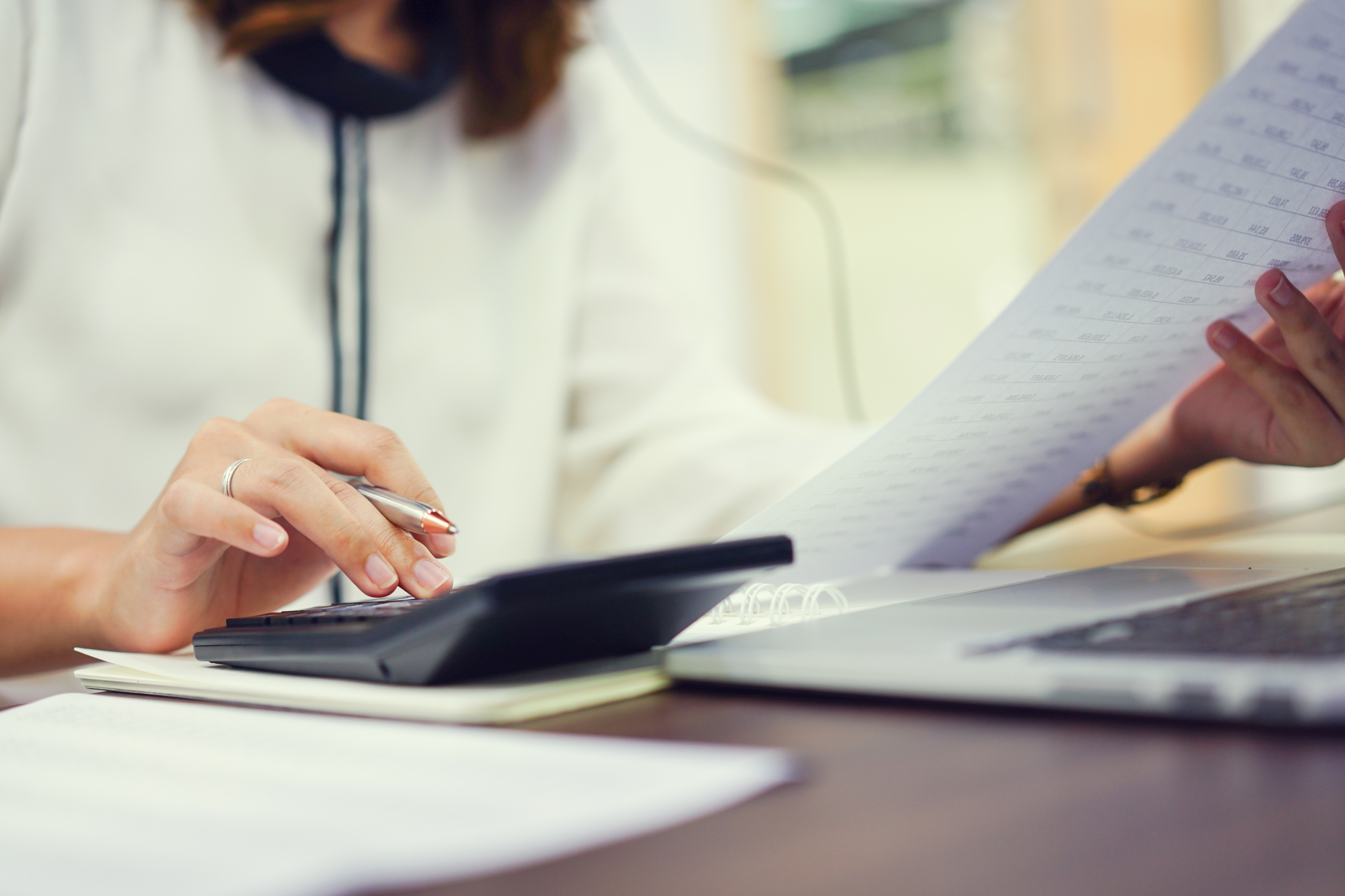 Image of business owner reading paperwork and typing into calculator