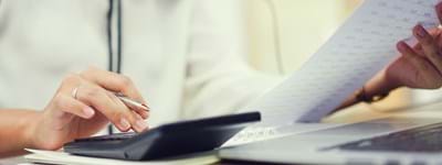 Image of business owner reading paperwork and typing into calculator